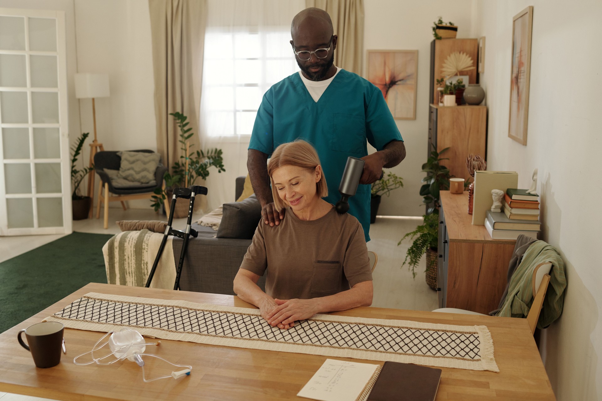 African American Caregiver Assisting Senior Woman with Massaging